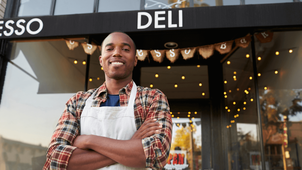 Business owner standing in front of his deli shop | Scott Legal, P.C. Business owner standing in front of his deli shop