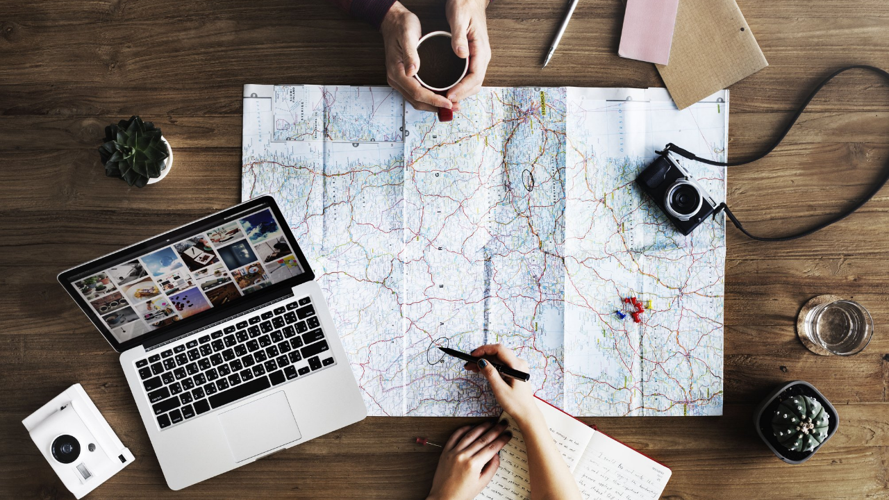 map, camera, laptop, pair planning out a trip | Scott Legal, P.C. map, camera, laptop, pair planning out a trip
