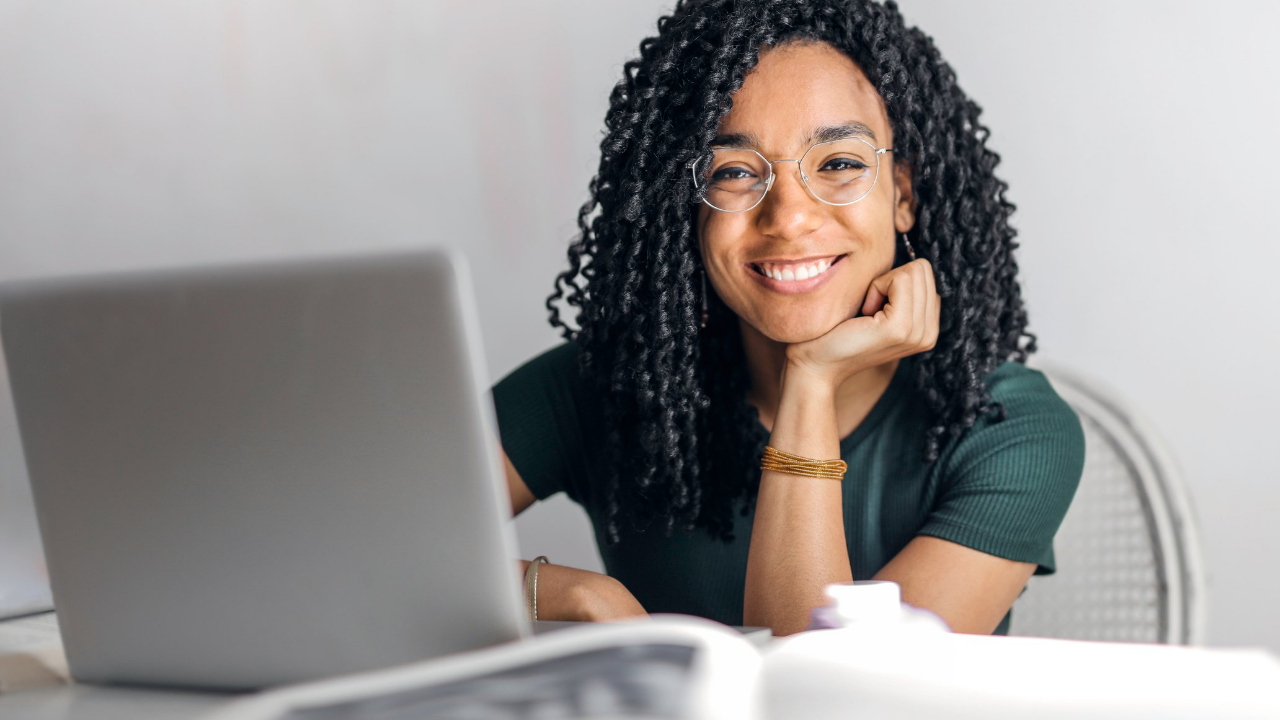 A woman smiling with her laptop set in front of her | Scott Legal, P.C. A woman smiling with her laptop set in front of her