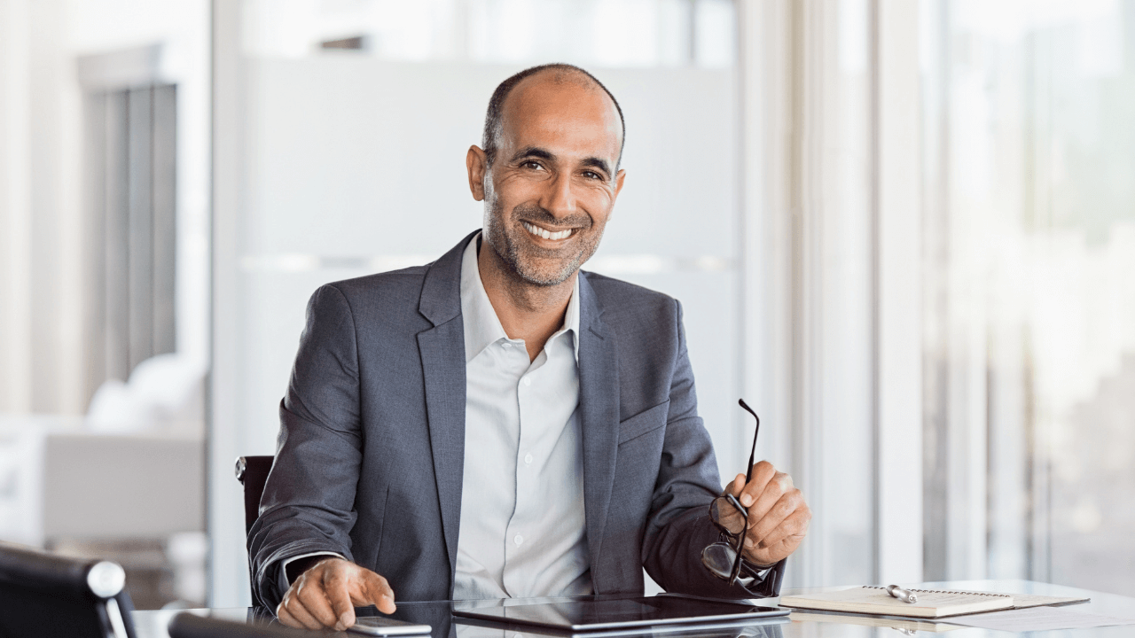 Business man smiling while sitting in his office | Scott Legal, P.C. Business man smiling while sitting in his office