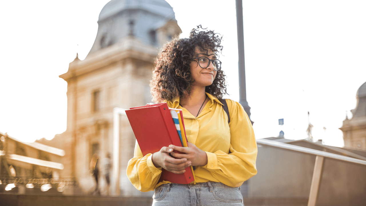 An international student holding her school books while standing outside the school | Scott Legal, P.C. An international student holding her school books while standing outside the school