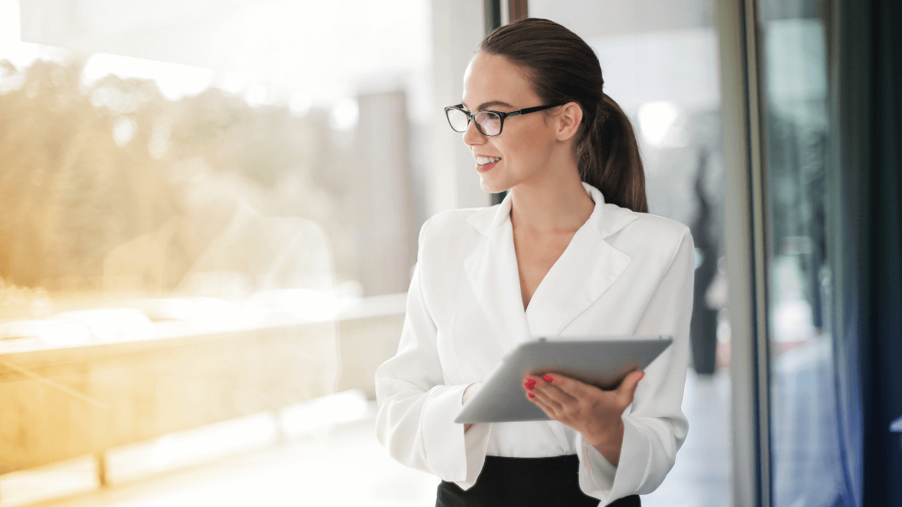 A professional standing in her office holding a tablet while smiling | Scott Legal, P.C. A professional standing in her office holding a tablet while smiling