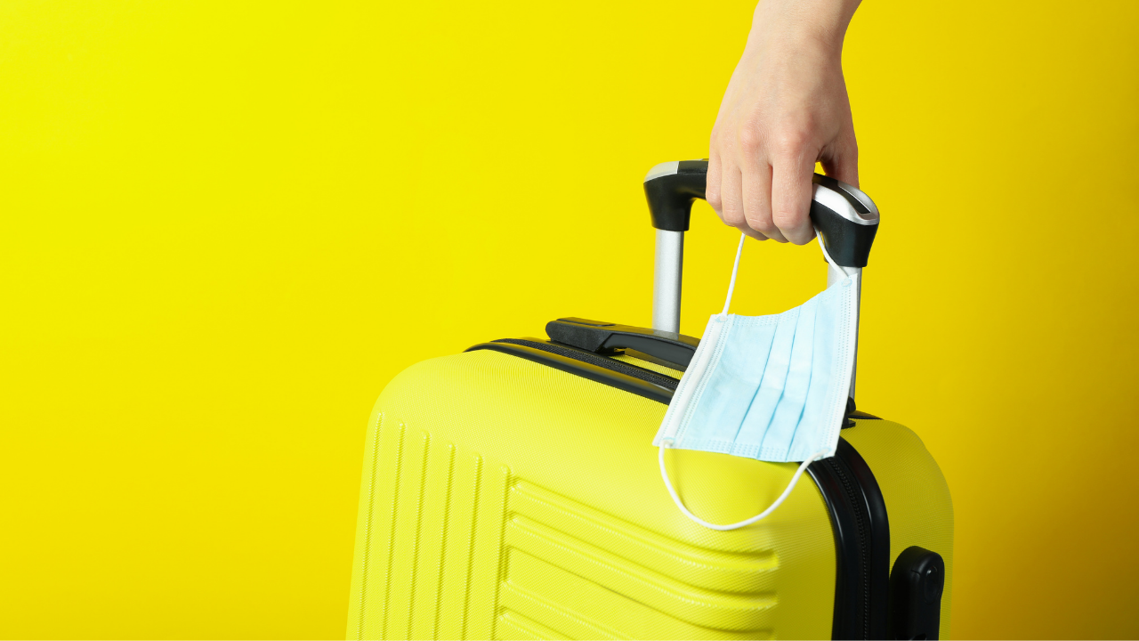 man pulling a yellow suitcase while holding a mask | Scott Legal, P.C. man pulling a yellow suitcase while holding a mask