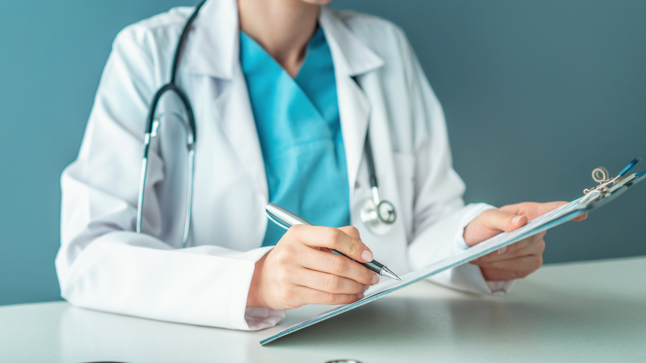 A doctor filling out a medical report on a clipboard | Scott Legal, P.C. A doctor filling out a medical report on a clipboard