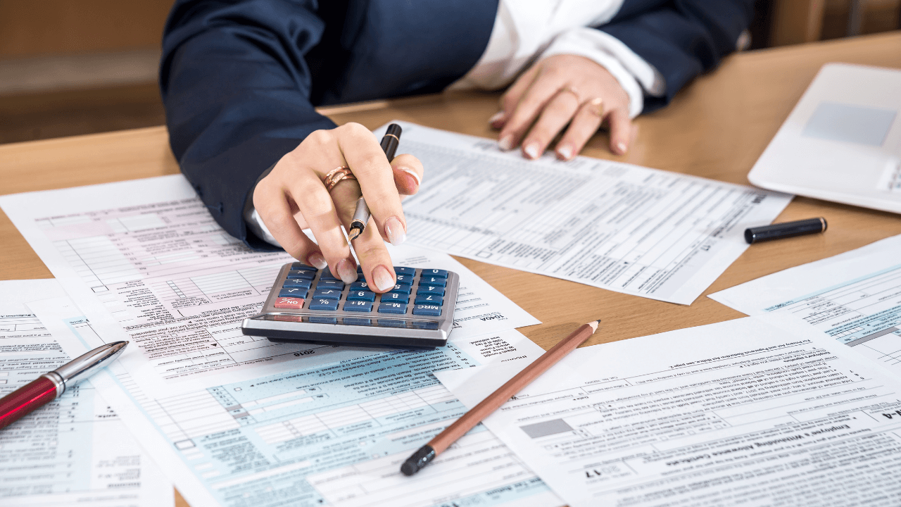 An accountant doing taxes on a desk full of financial documents | Scott Legal, P.C. An accountant doing taxes on a desk full of financial documents