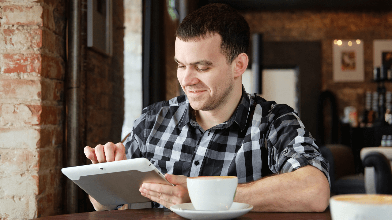 A man sitting in a cafe working on his tablet | Scott Legal, P.C. A man sitting in a cafe working on his tablet