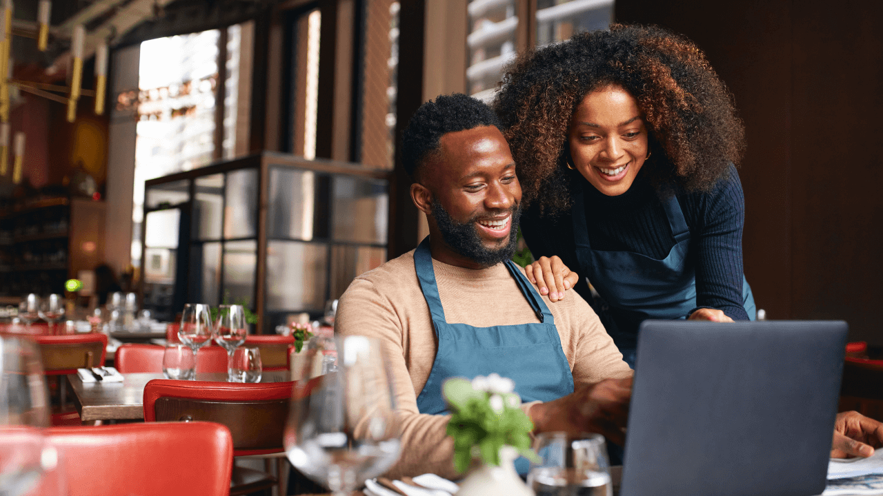 Two business owners smiling at something they are looking at on a laptop | Scott Legal, P.C. Two business owners smiling at something they are looking at on a laptop