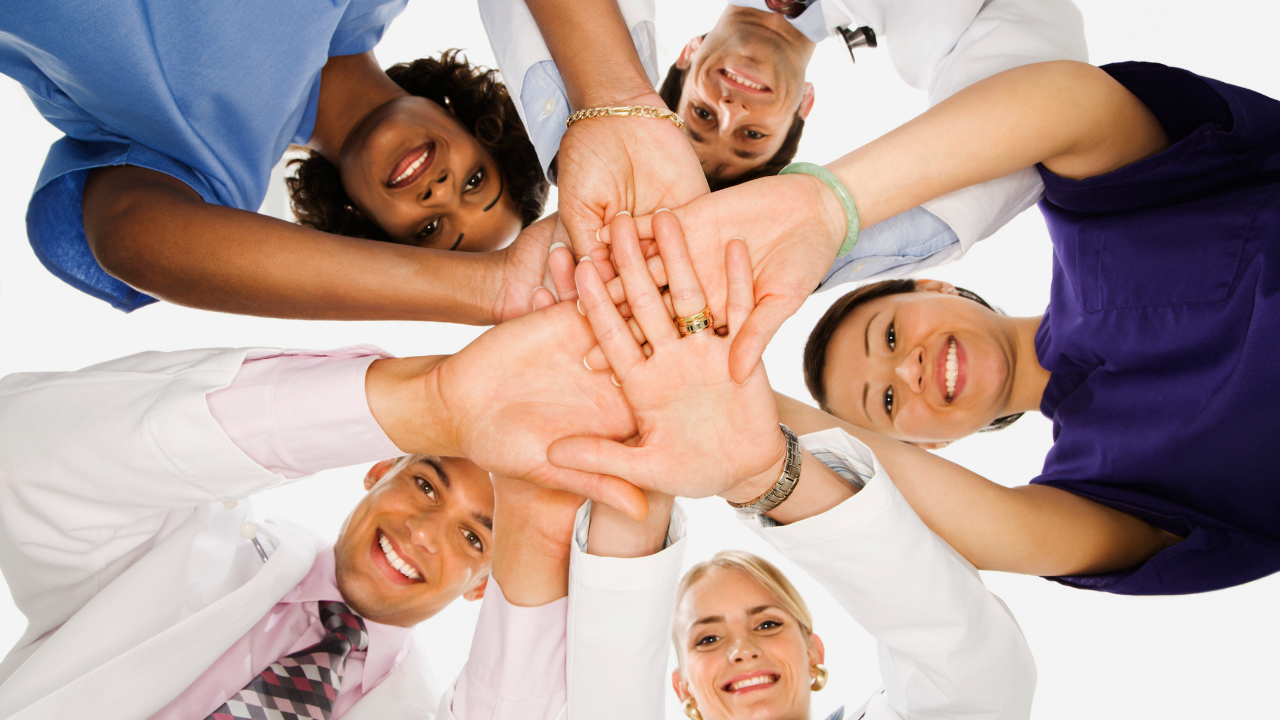 A group of healthcare workers joining hands in cooperation | Scott Legal, P.C. A group of healthcare workers joining hands in cooperation
