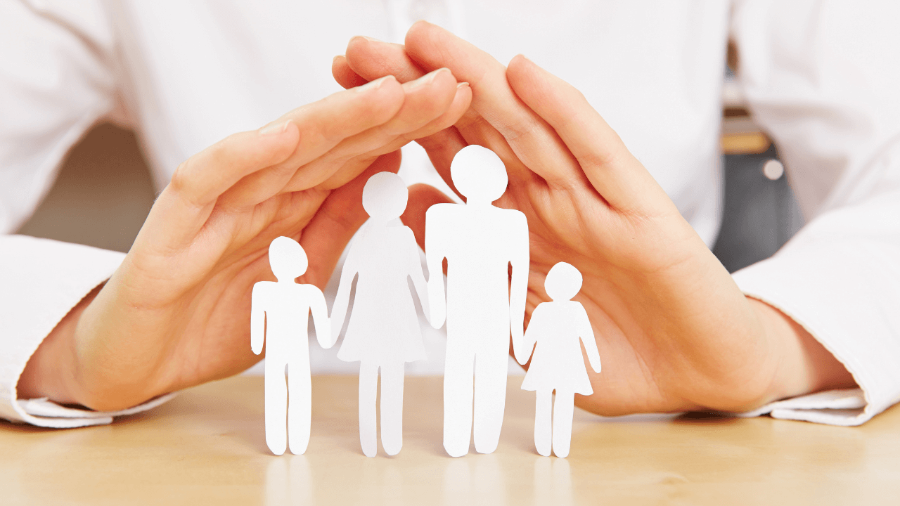 A hand shielding paper cut out of a family | Scott Legal, P.C. A hand shielding paper cut out of a family