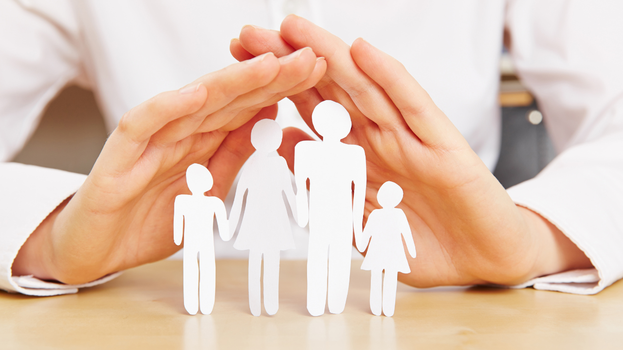 A hand protecting paper cut outs of a family | Scott Legal, P.C. A hand protecting paper cut outs of a family