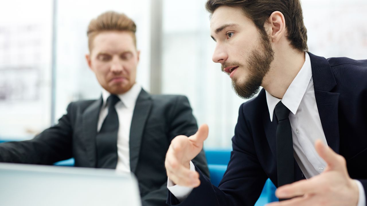 Two economist in business suits speaking with each other | Scott Legal, P.C. Two economist in business suits speaking with each other
