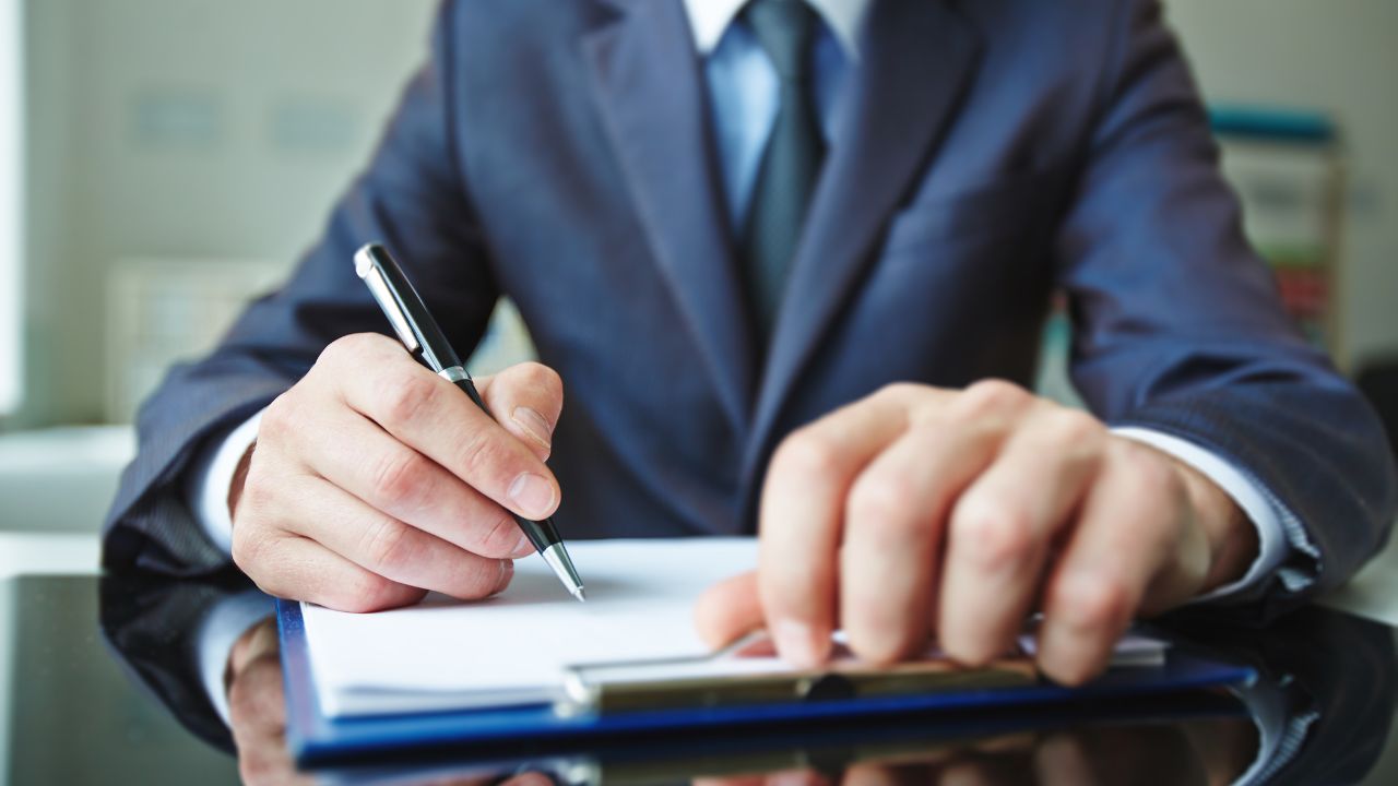 A man in a suit getting ready to sign some paperwork | Scott Legal, P.C. A man in a suit getting ready to sign some paperwork