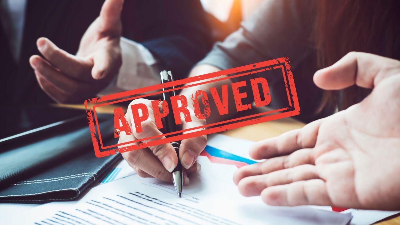 Approed stamp over a group of business men and women signing documents | Scott Legal, P.C. Approed stamp over a group of business men and women signing documents