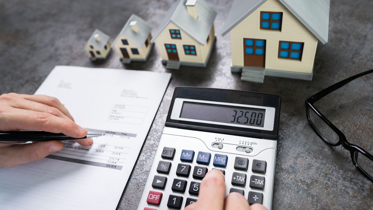 Houses, a calculator, and tax form on a desk | Scott Legal, P.C. Houses, a calculator, and tax form on a desk