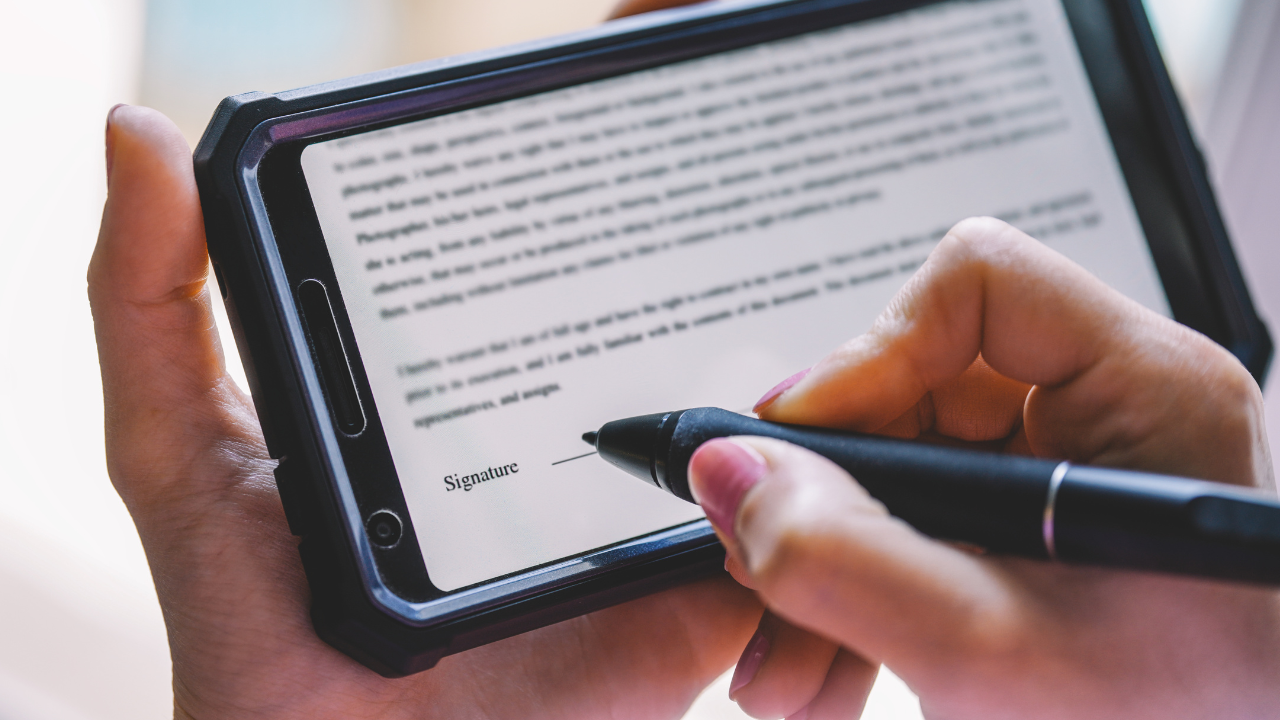 A man or woman holding a tablet and signing electronically | Scott Legal, P.C. A man or woman holding a tablet and signing electronically