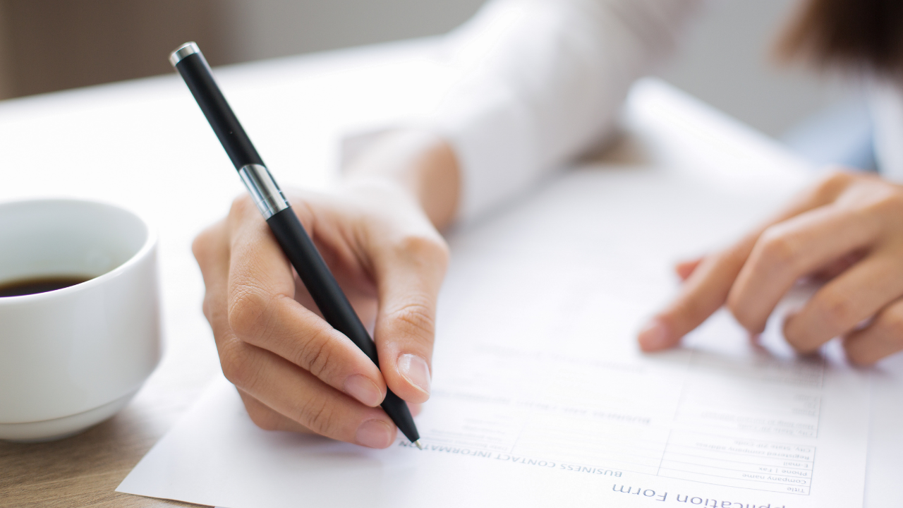 A woman filling out an application form | Scott Legal, P.C. A woman filling out an application form