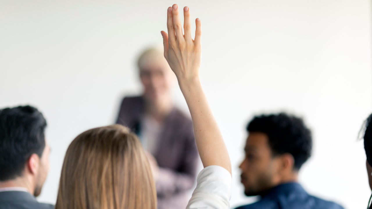 A woman raising her hand to ask a question | Scott Legal, P.C. A woman raising her hand to ask a question