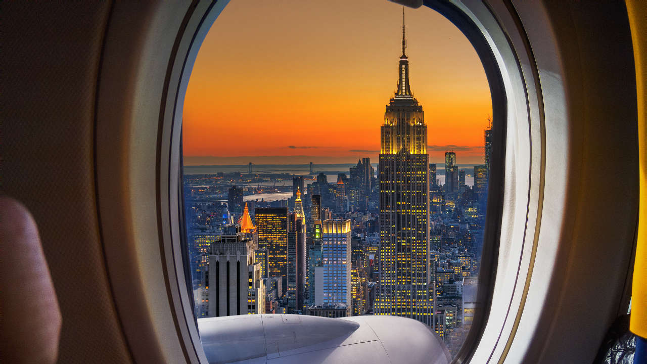 A traveller looking out an airplane window at a city view | Scott Legal, P.C. A traveller looking out an airplane window at a city view