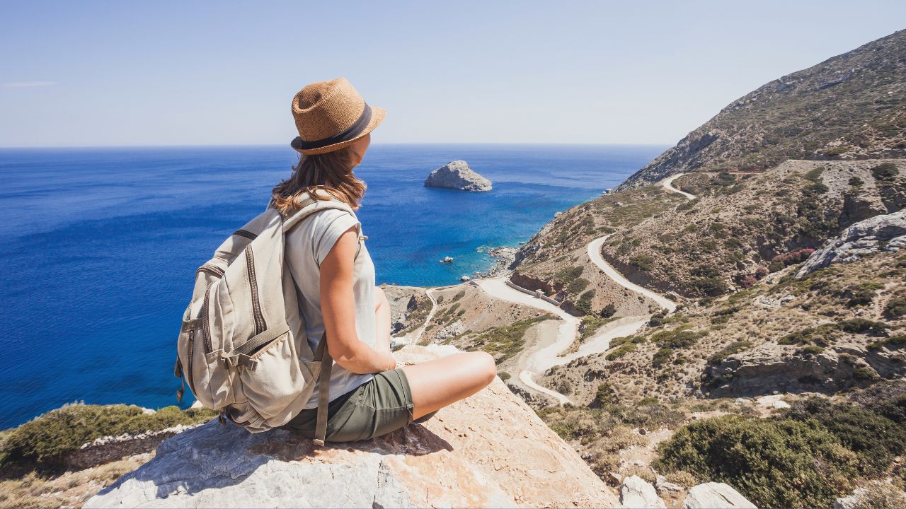 A woman sitting on a hill overlooking a travel destination | Scott Legal, P.C. A woman sitting on a hill overlooking a travel destination