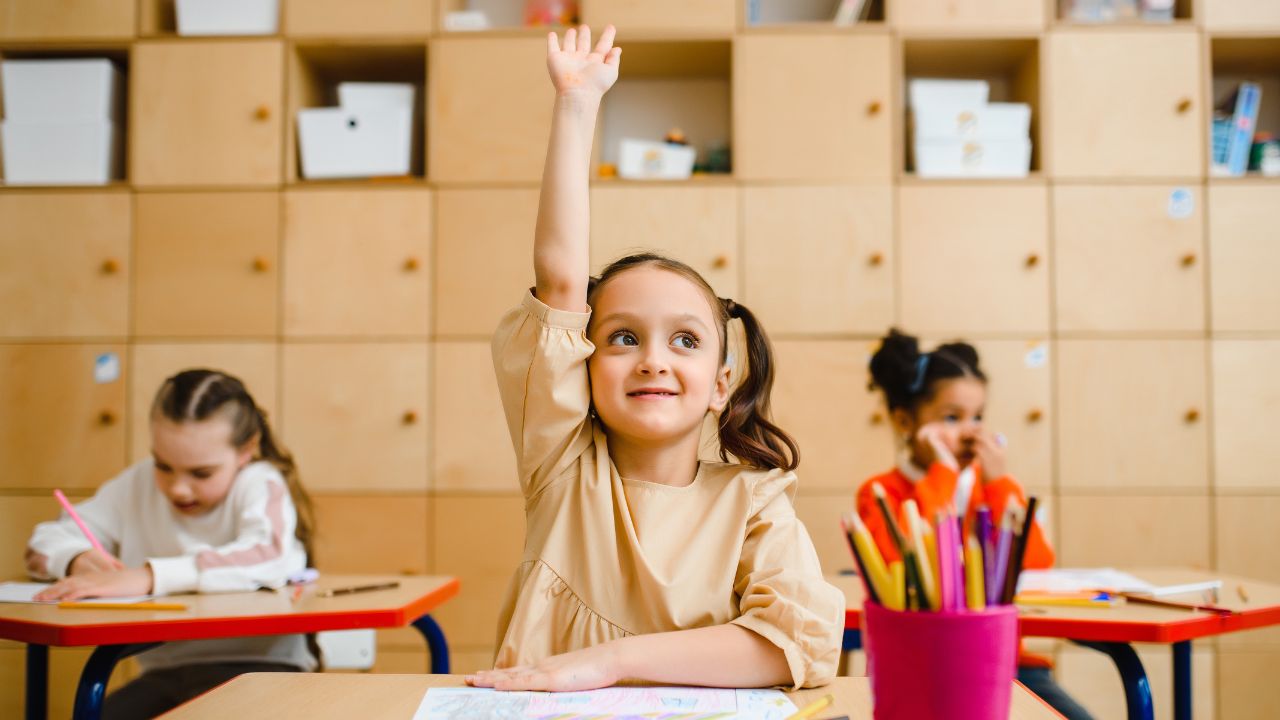 A child raising her hand to answer a question at school | Scott Legal, P.C. A child raising her hand to answer a question at school