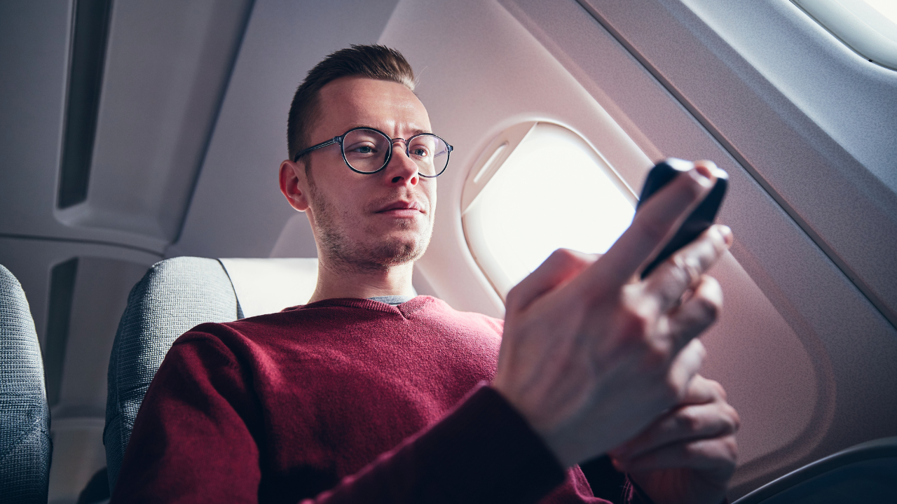 A man checking his connecting flight while on his current flight | Scott Legal, P.C. A man checking his connecting flight while on his current flight