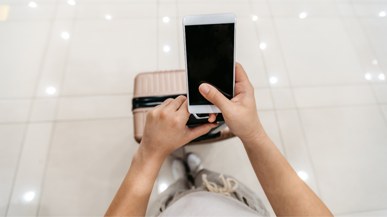 a man holding a cell phone in the airport | Scott Legal, P.C. a man holding a cell phone in the airport