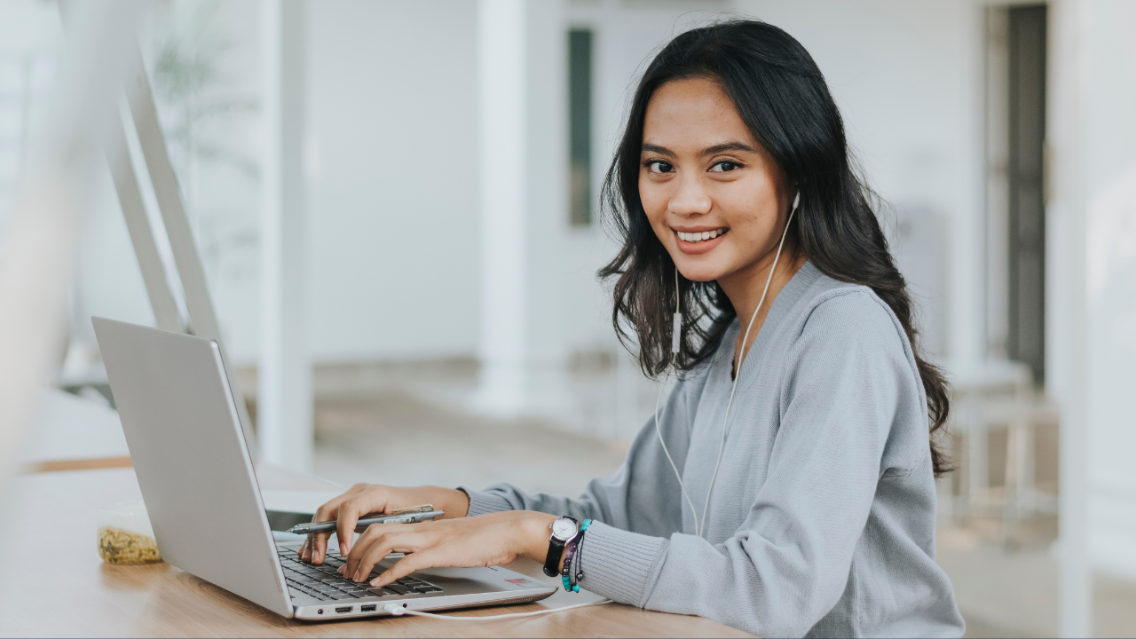 A woman working on her laptop while smiling | Scott Legal, P.C. A woman working on her laptop while smiling