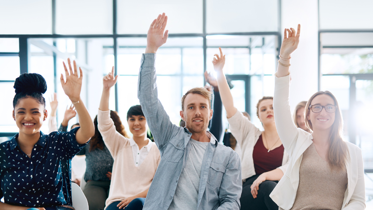 A group of people in a Q&A session raising their hands to ask questions | Scott Legal, P.C. A group of people in a Q&A session raising their hands to ask questions