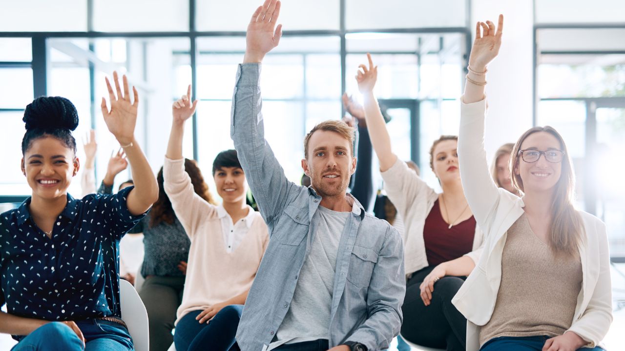 A group of people with their hands raised to ask questions | Scott Legal, P.C. A group of people with their hands raised to ask questions