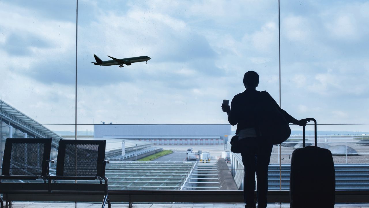 A woman standing in an airport watching planes take off | Scott Legal, P.C. A woman standing in an airport watching planes take off