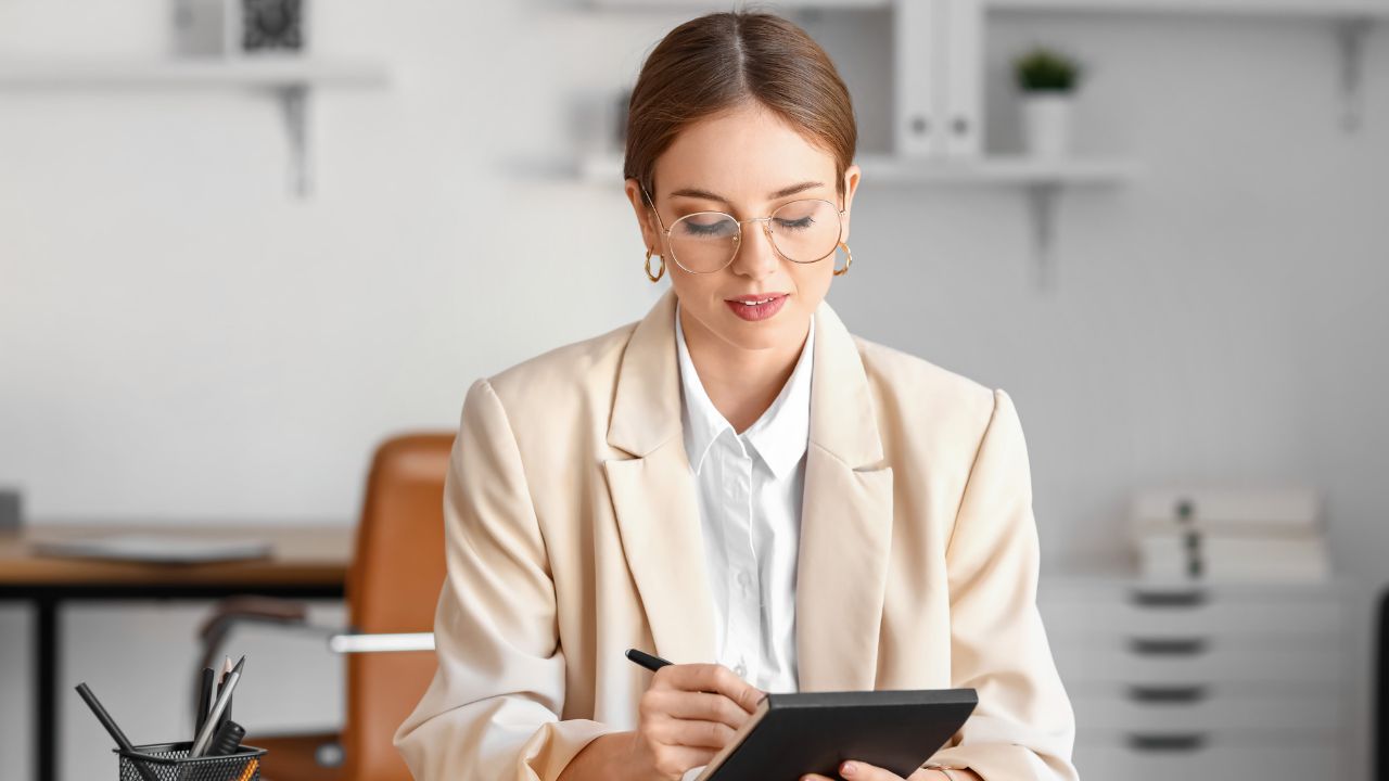 A woman taking notes in her home office | Scott Legal, P.C. A woman taking notes in her home office