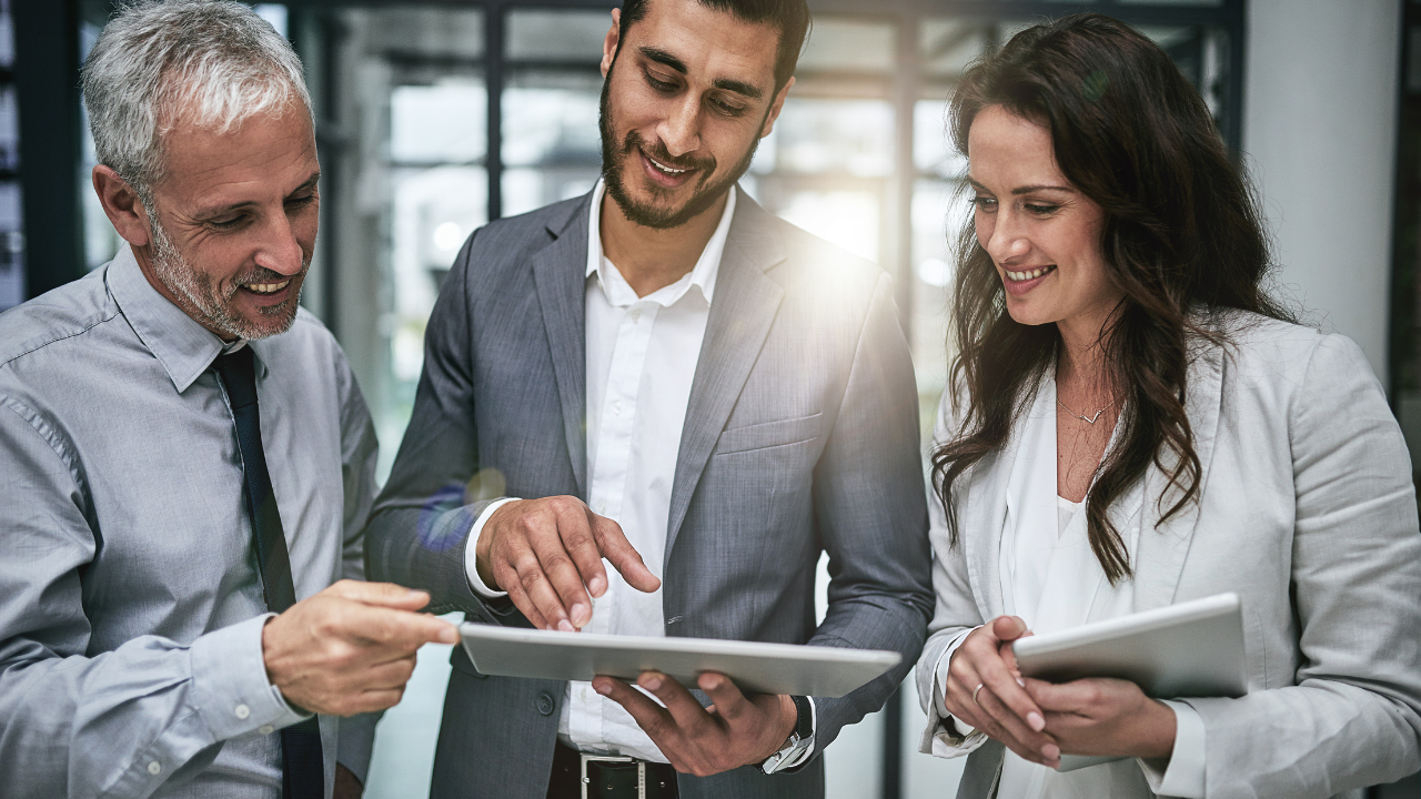 A group of professionals gathered to look at something on an ipad | Scott Legal, P.C. A group of professionals gathered to look at something on an ipad