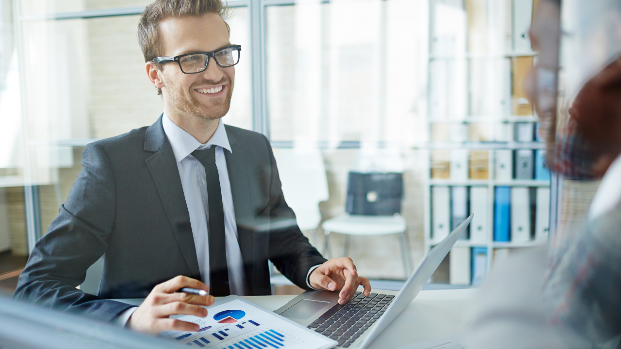A consultant speaking to a client at his desk with a laptop in front of him | Scott Legal, P.C. A consultant speaking to a client at his desk with a laptop in front of him