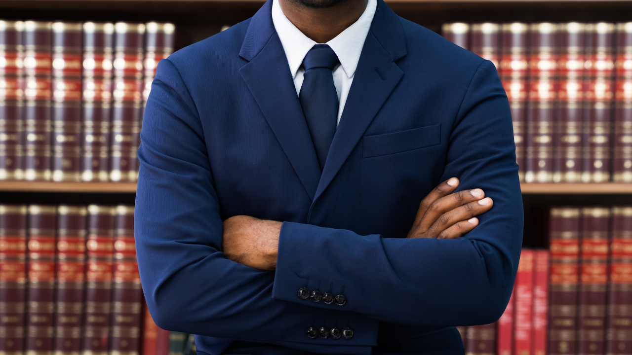 A lawyer standing in front of legal books on a bookshelf | Scott Legal, P.C. A lawyer standing in front of legal books on a bookshelf