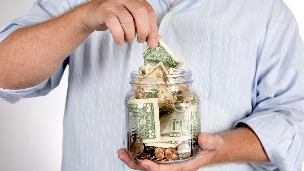 A man pulling money out of his money jar | Scott Legal, P.C. A man pulling money out of his money jar
