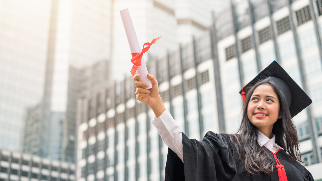 A graduate holding up a bachelor's degree | Scott Legal, P.C. A graduate holding up a bachelor's degree