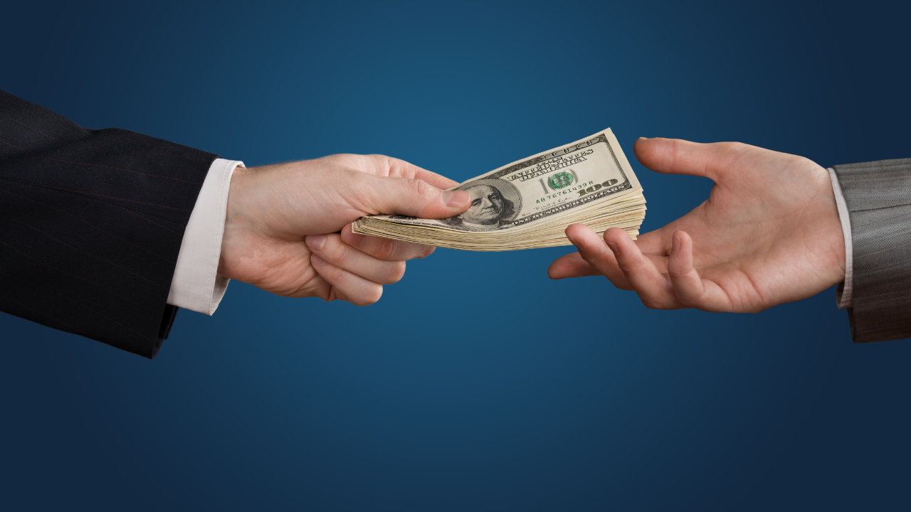 A business professional handing money to another as a loan | Scott Legal, P.C. A business professional handing money to another as a loan