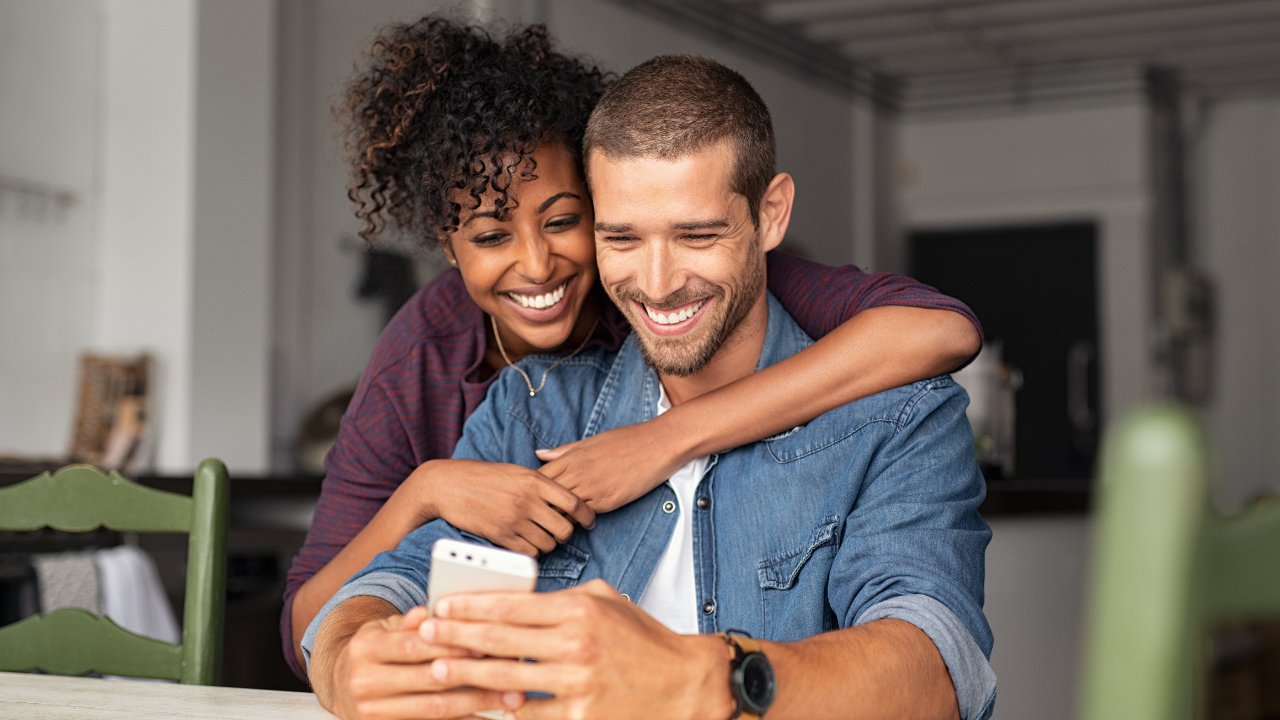 A happy couple looking at a recent green card approval | Scott Legal, P.C. A happy couple looking at a recent green card approval
