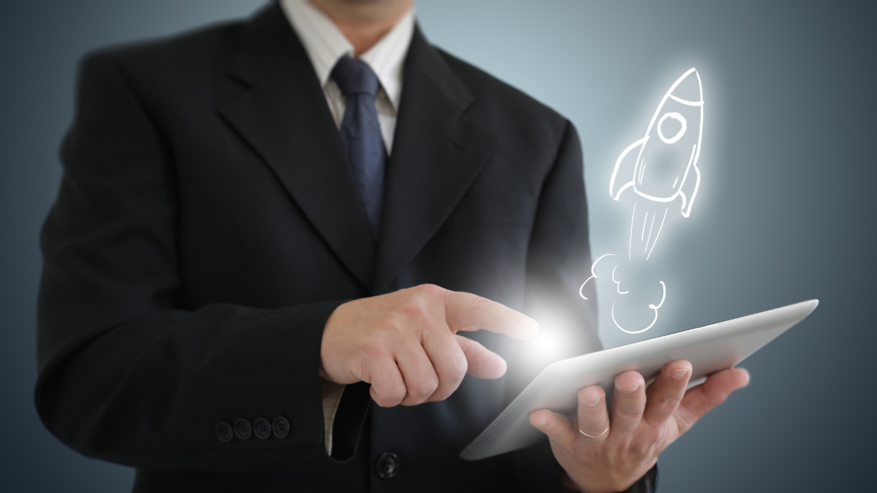 A successful business man holding a tablet with a rocket blasting out of it | Scott Legal, P.C. A successful business man holding a tablet with a rocket blasting out of it