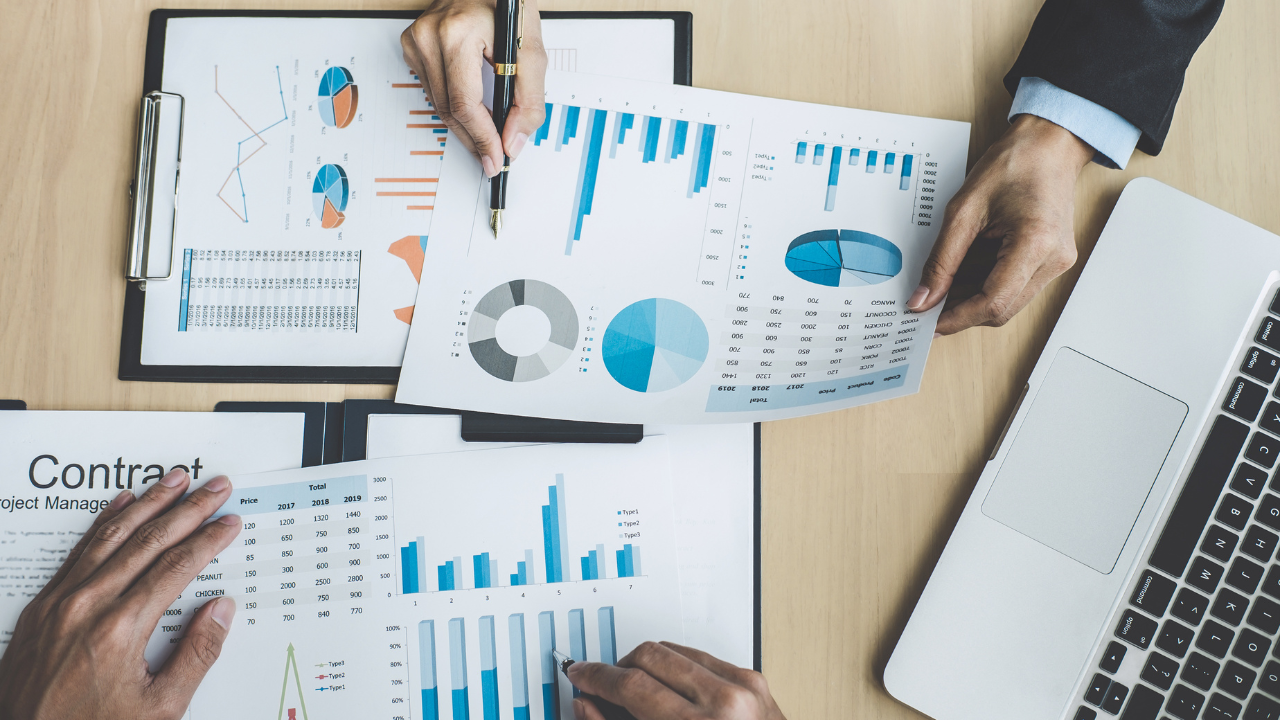 A collection of financial charts on a work table with a laptop | Scott Legal, P.C. A collection of financial charts on a work table with a laptop