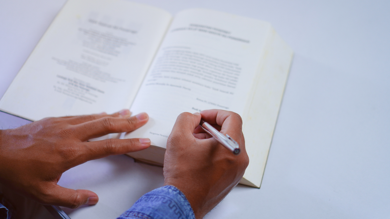 A man writing in a published book | Scott Legal, P.C. A man writing in a published book