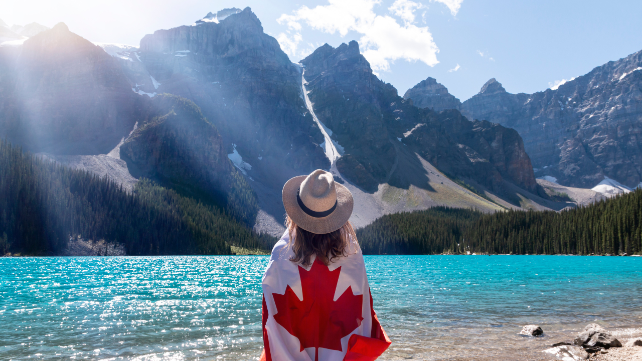 A woman travelling to see the mountains with a Canadian flag | Scott Legal, P.C. A woman travelling to see the mountains with a Canadian flag