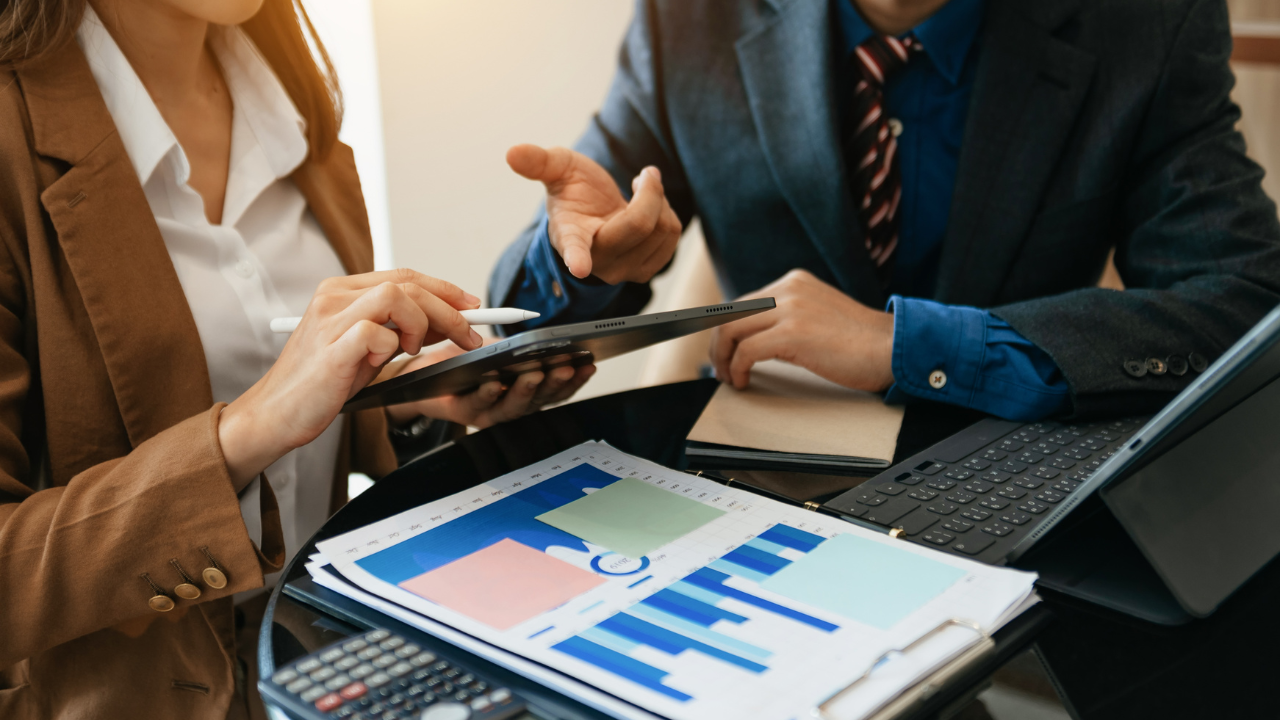 Two business professionals discussing finances over charts | Scott Legal, P.C. Two business professionals discussing finances over charts