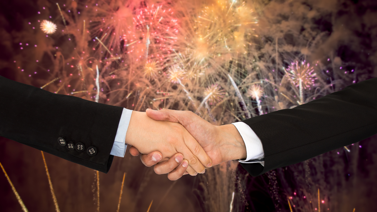 two business professionals shaking hands with fireworks in the background | Scott Legal, P.C. two business professionals shaking hands with fireworks in the background