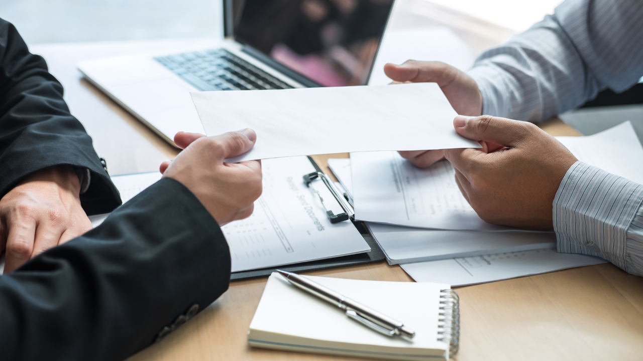An employer handing an offer letter to a potential employee | Scott Legal, P.C. An employer handing an offer letter to a potential employee