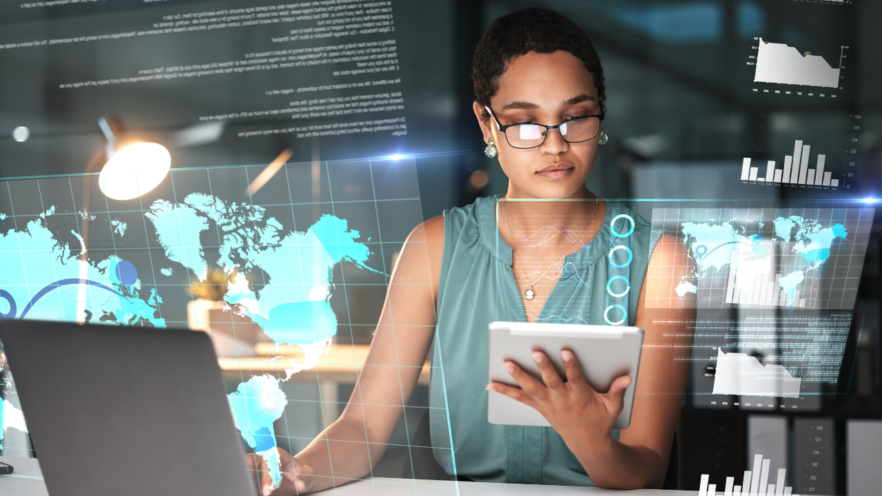 A woman working on a tablet and laptop with global images on the screen | Scott Legal, P.C. A woman working on a tablet and laptop with global images on the screen
