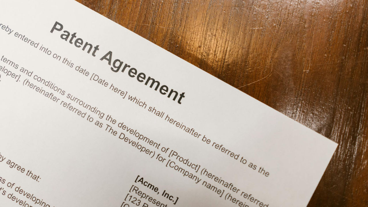 E-2 Visa Investment with Intellectual Property | Scott Legal, P.C. A patent agreement document on a table.